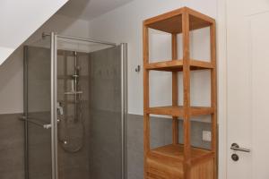 a bathroom with a shower and a wooden shelf at Ostseefeeling in Wustrow +8 photos