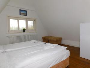 a white bed in a room with a window at Puppenhaus in Ahrenshoop