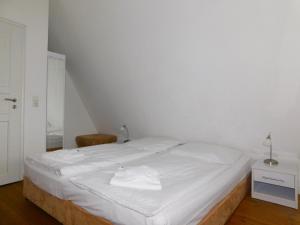 a white bed in a room with a chair at Puppenhaus in Ahrenshoop