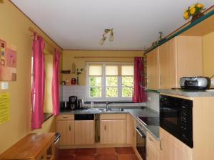 a kitchen with a sink and a window with red curtains at Haus Tina in Ahrenshoop