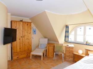a bedroom with a bed and a tv and a chair at Haus Tina in Ahrenshoop
