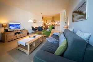 a living room with a blue couch and a tv at Suite Meeresrauschen in Ahrenshoop