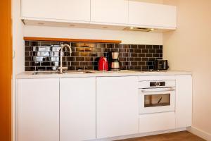 a kitchen with white cabinets and a black tile wall at Anker Haus Sanddorn in Althagen