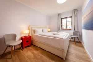 a bedroom with a bed with a red cabinet and two chairs at Anker Haus Sanddorn in Althagen