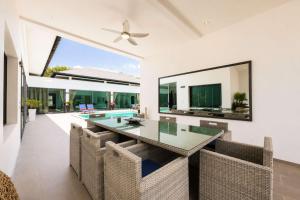 a dining room with a glass table and chairs at Exclusive Tropical Living! Elegant 4BR Villa Destiny with Salt Pool in Rawai Beach