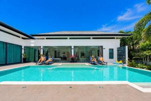 a group of people sitting around a swimming pool at Exclusive Tropical Living! Elegant 4BR Villa Destiny with Salt Pool in Rawai Beach