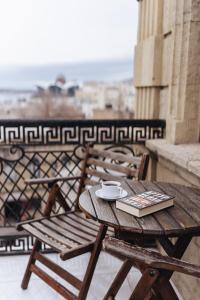 a wooden table and chairs on a balcony with a book at Seven Rooms Boutique Hotel in Baku