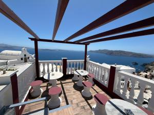 a balcony with tables and chairs and a view of the ocean at Maryloujohn Villas Oia in Oia
