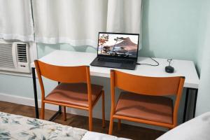 a laptop computer sitting on a desk with two chairs at Apto Central com Wi-Fi Rápido e Workspace in Niterói +7 photos