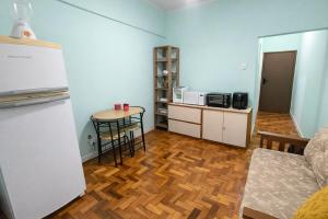 a room with a kitchen with a table and a refrigerator at Apto Central com Wi-Fi Rápido e Workspace in Niterói