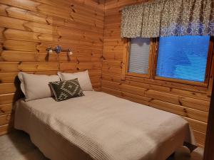 a bed in a log cabin with a window at Ilvesrinne - Cosy Fell-Side Cottage in Iso-Syöte in Syöte