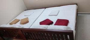 a white bed with three red pillows on it at gururesidency in Tiruvannāmalai +1 photo