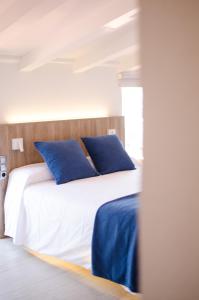 ein Schlafzimmer mit einem Bett mit blauen Kissen in der Unterkunft Hotel Nereida in L'Estartit