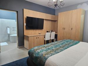 a bedroom with a bed and a flat screen tv at TACOA Boutique Hotel in Westonaria
