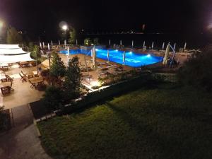 Oasi Bianca في Pomposa: مسبح في الليل مع طاولات وكراسي