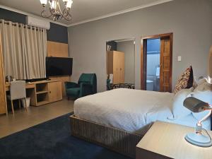 a bedroom with a bed and a desk and a television at TACOA Boutique Hotel in Westonaria