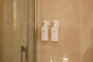 two bottles ofodorizers are on the wall of a shower at Fenisien Boutique Rooms in Contursi +14 photos