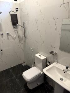 a white bathroom with a toilet and a sink at Surf del mar in Arugam Bay