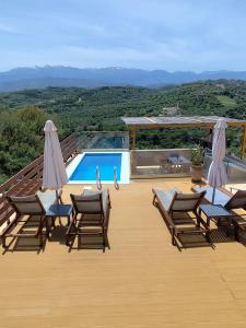 a wooden deck with chairs and a swimming pool at Wish Sea & Mountain View in Stalos