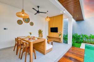 a dining room with a table and chairs and a television at Tapan Harmony Villa Ubud in Ubud