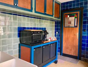 a kitchen with a microwave on a blue tiled wall at B&B Huis Billiet in Bruges