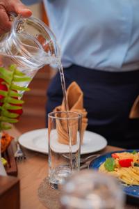 a person is pouring water into a glass on a table at Hotel Sampada Boutique in Pokhara