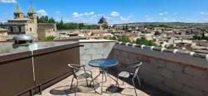 a balcony with two chairs and a table and a city at Hotel Real De Toledo in Toledo