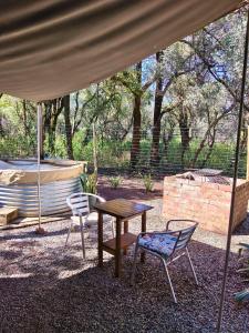 a table and two chairs under a tent at Romantic Hot Tub Retreat - Ndlovu 33 Tiny Home, Big 5 reserve in Klipdrift