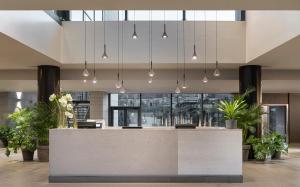 a lobby with a reception counter with potted plants at MOVE Hotels Venezia Nord in Mogliano Veneto