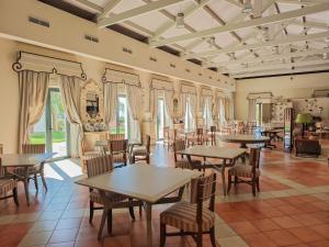 ein Esszimmer mit Tischen, Stühlen und Fenstern in der Unterkunft AZZ Castellar Hacienda El Alcornocal in Castellar de la Frontera