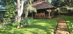 a house with a thatch roof and a garden at Moshono WiDa Lodge in Arusha