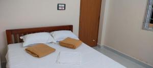 a white bed with two brown pillows on it at gururesidency in Tiruvannāmalai