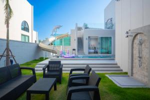 a group of benches sitting on the grass in front of a house at Luma & Malta PoolVilla Cha-am in Sathani Nong Ta Phot