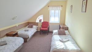 a room with two beds and a red chair at Krkonošská chaloupka in Černý Dŭl