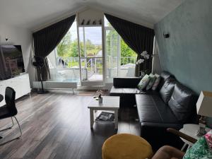 a living room with a black leather couch and a table at Amsterdam Countryside met Airco ,Geweldig uitzicht, luxe keuken,wasmachine,droger,gratis fietsen in Den Ilp