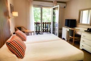 a bedroom with two beds and a desk and a television at Les Trois Soleils in Saint-Céré