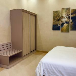 a bedroom with a bed and a cabinet with two paintings at Mandarin Alshamal Hotel Apartments in Riyadh +55 photos