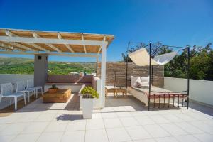 a patio with a pergola and a couch and chairs at Villa Ikaros in Agia Triada