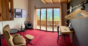 a room with chairs and a desk and a balcony at Auszeit-Hotel Z Aeschiried in Aeschi