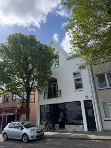 a car parked in front of a white building at Mel's Pintxos winebar & Aparthotel in Zandvoort