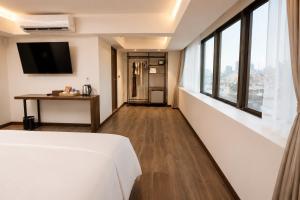 a hotel room with a bed and a desk and windows at The Wang Yaowarat Hotel in Bangkok