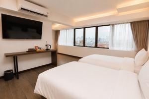 a hotel room with two beds and a flat screen tv at The Wang Yaowarat Hotel in Bangkok
