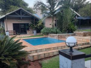 a swimming pool in front of a house at Arotin Game Lodge in Brits