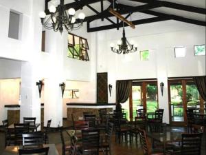 a dining room with chairs and tables and chandeliers at Arotin Game Lodge in Brits