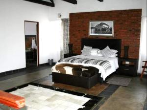 a bedroom with a bed and a brick wall at Arotin Game Lodge in Brits +39 photos
