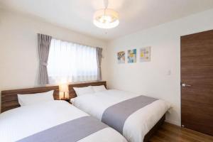 two beds in a bedroom with a window at HIRO HOUSE Marugame - 丸亀駅徒歩5分 in Marugame