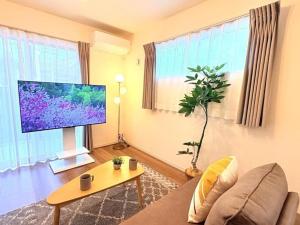 a living room with a large flat screen tv at HIRO HOUSE Marugame - 丸亀駅徒歩5分 in Marugame