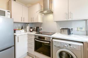 a kitchen with white cabinets and a washer and dryer at 2 Bed in Bideford oc-rives in Bideford