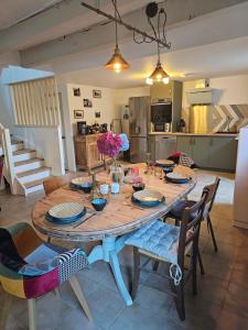 a dining room table with chairs and a kitchen at Ker Adèle, longère cosy au cœur d'un bois in Ploërdut