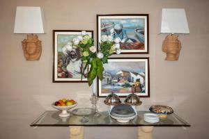 a table with a vase of flowers and paintings at Hotel Sirio in Lampedusa